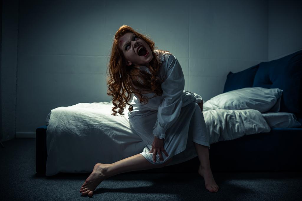 Демоническая жуткая девушка в ночной рубашке кричит в спальне
 - Фото, изображение