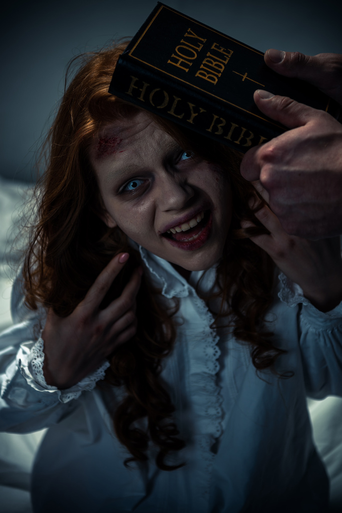 εξορκιστής κρατώντας Αγία Γραφή κοντά εμμονή δαιμονική κορίτσι στην κρεβατοκάμαρα  - Φωτογραφία, εικόνα