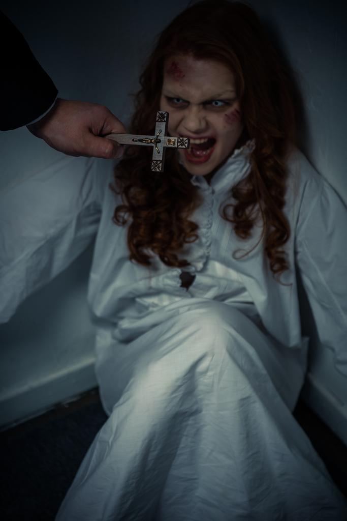 esorcista che tiene la croce davanti a un demone femmina urlante
 - Foto, immagini