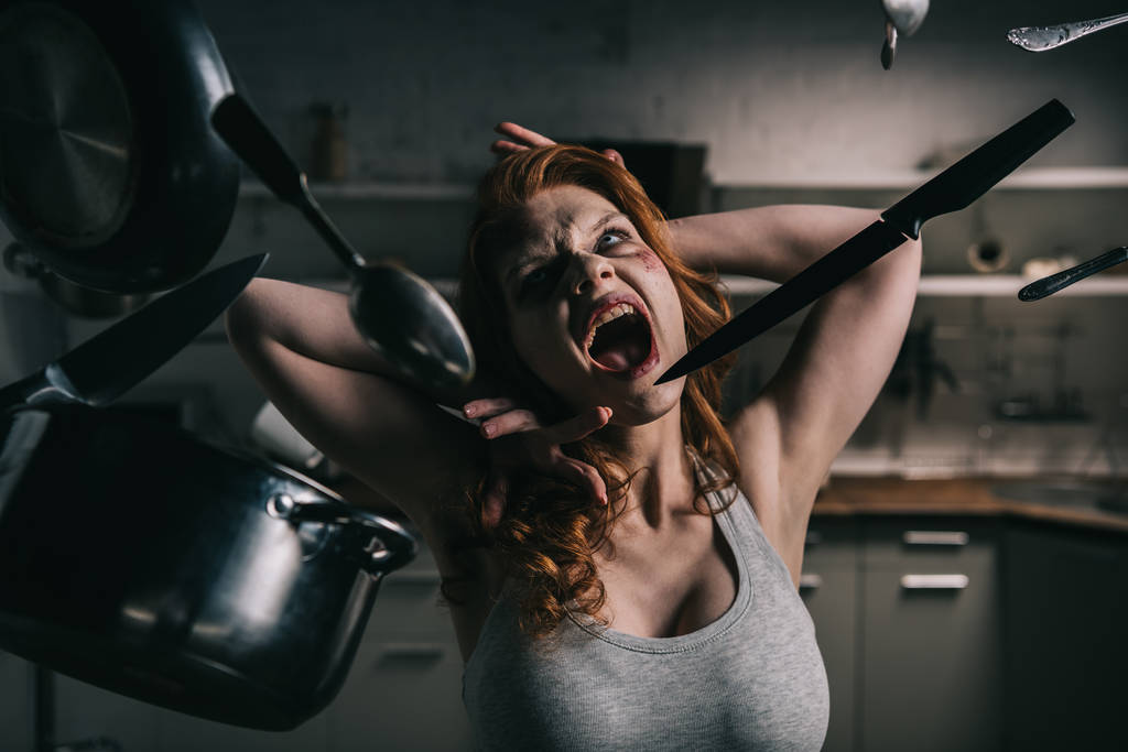 Dämonisch schreiendes Mädchen mit schwebendem Geschirr in Küche - Foto, Bild