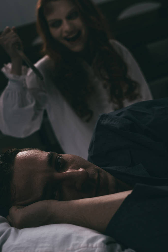 foyer sélectif de démoniaque riant femme avec couteau debout sur l'homme au lit
 - Photo, image