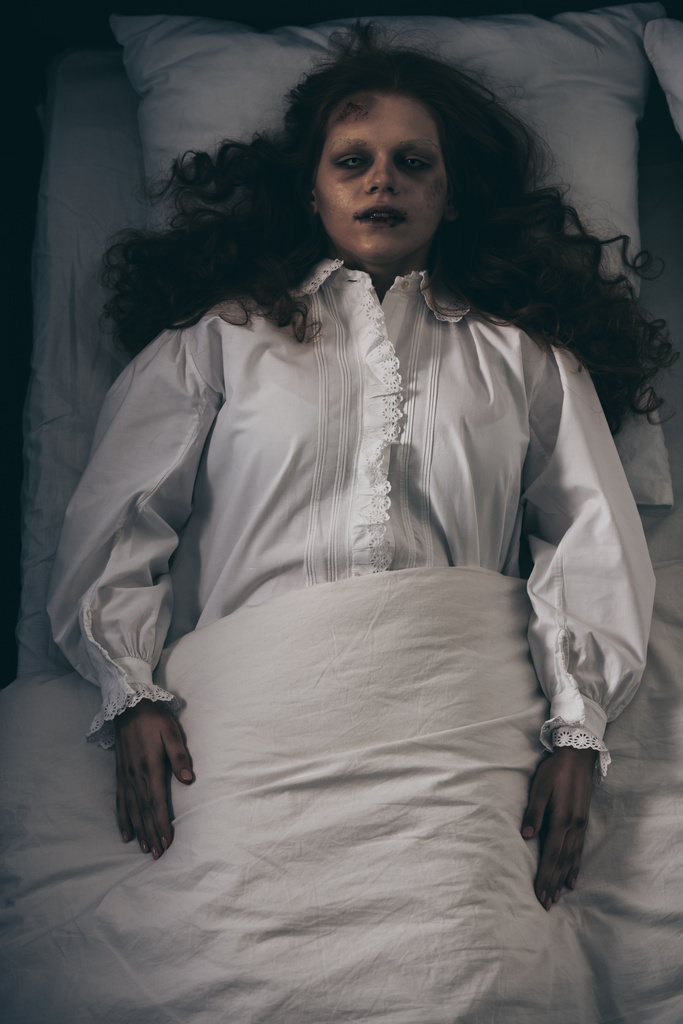 Draufsicht auf gruselige junge Frau im Nachthemd, die im Bett liegt - Foto, Bild