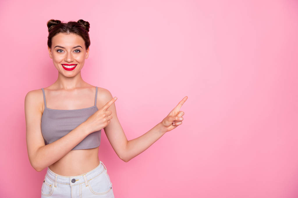 Photo of millennial lady pretty buns red pomade amazing shapes indicating finger empty space show low prices wear casual grey short top naked belly isolated pink color background - Photo, Image