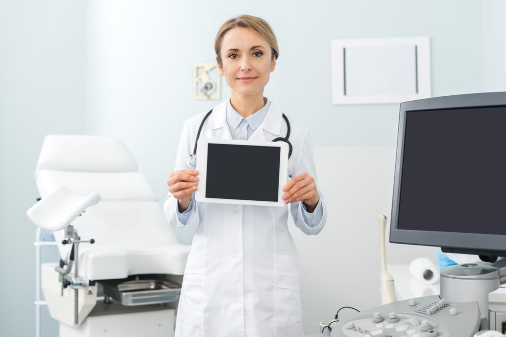 Ärztin zeigt digitales Tablet mit leeren Bildschirmen in Klinik mit Ultraschallscanner - Foto, Bild