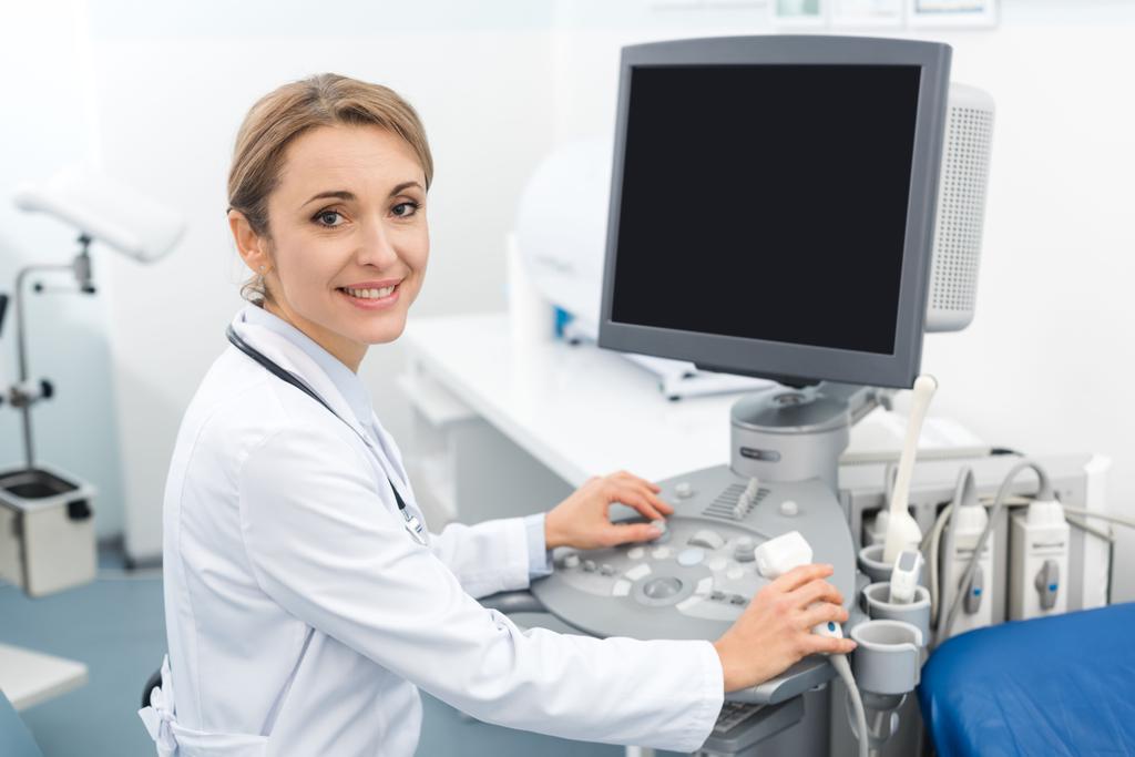 pozitivní lékař pracující s ultrazvukovým skenerem s prázdným displejem na klinice  - Fotografie, Obrázek