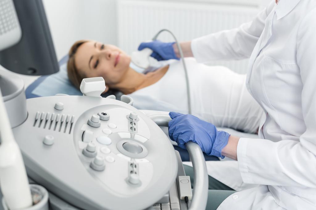 Junge Ärztin untersucht Schilddrüse einer Patientin mit Ultraschall in Klinik - Foto, Bild