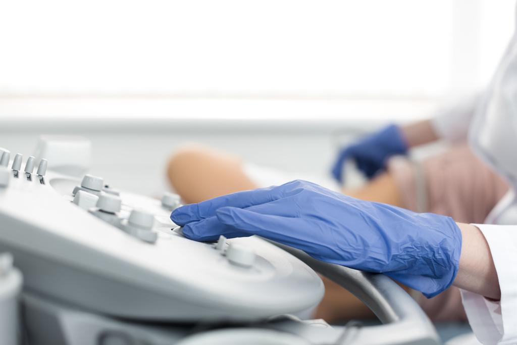 Ausgeschnittene Ansicht des Arztes, der die Niere des Patienten mit Ultraschall in der Klinik untersucht - Foto, Bild