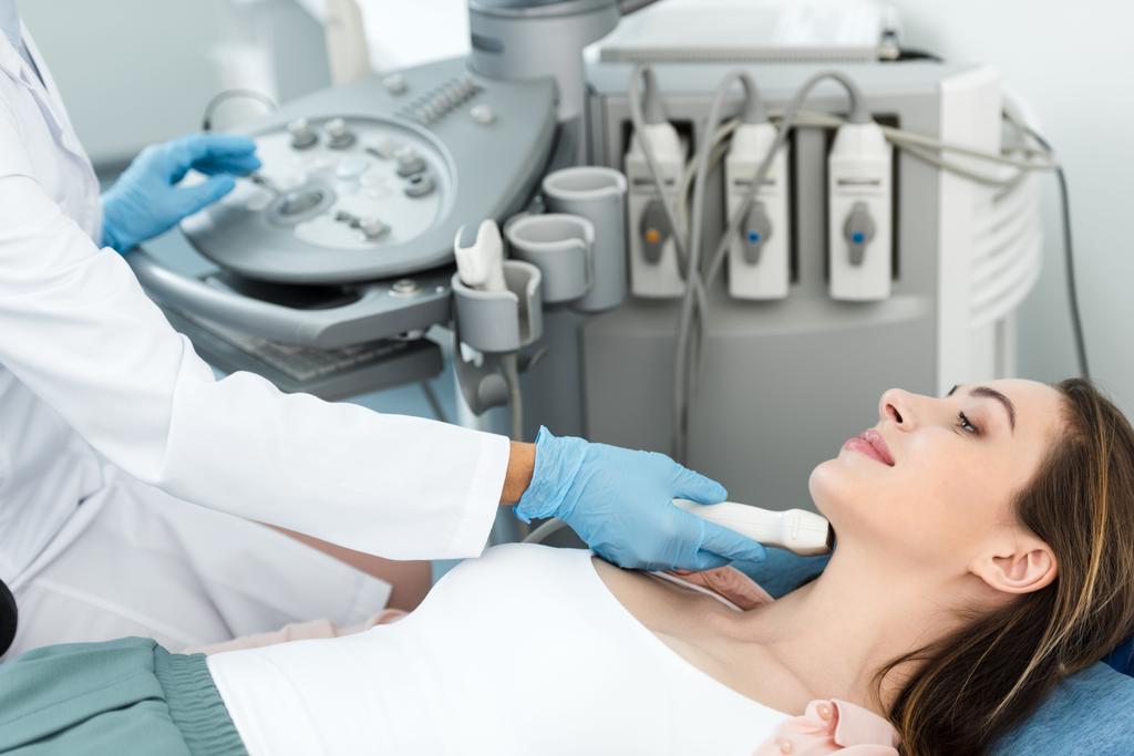 orvos fehér köpenyben vizsgálja pajzsmirigy nőbeteg ultrahang vizsgálat klinikán - Fotó, kép