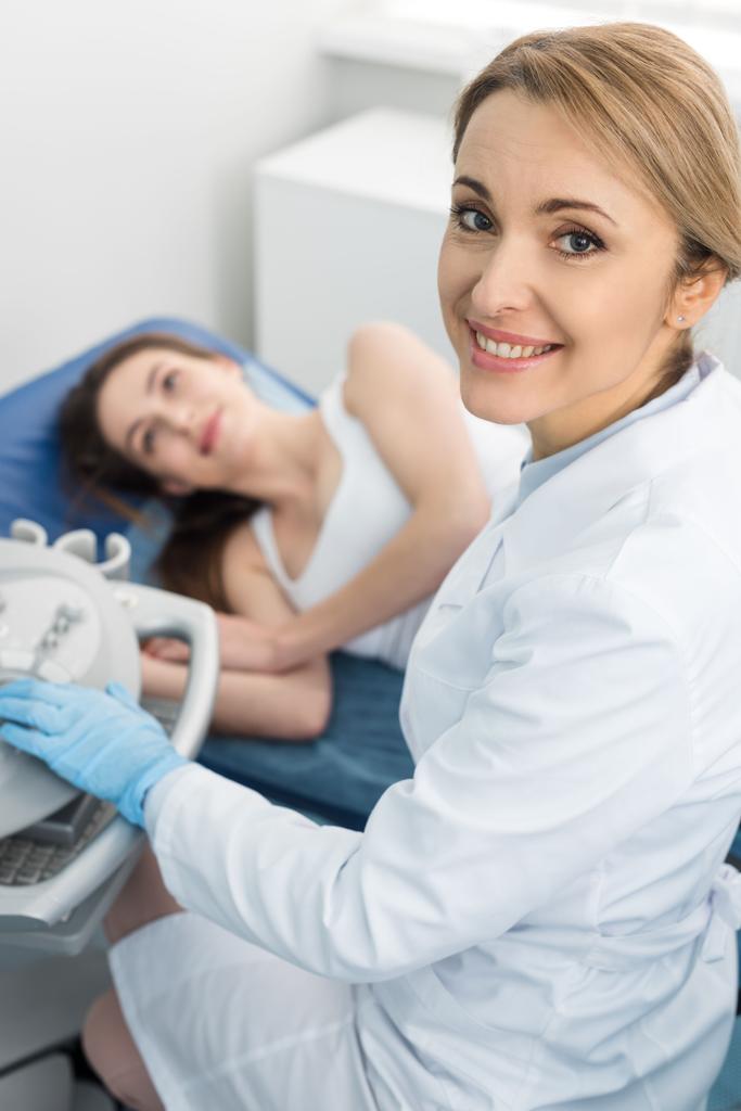 médico sonriente examinando riñón de paciente femenina con ecografía en clínica
   - Foto, imagen