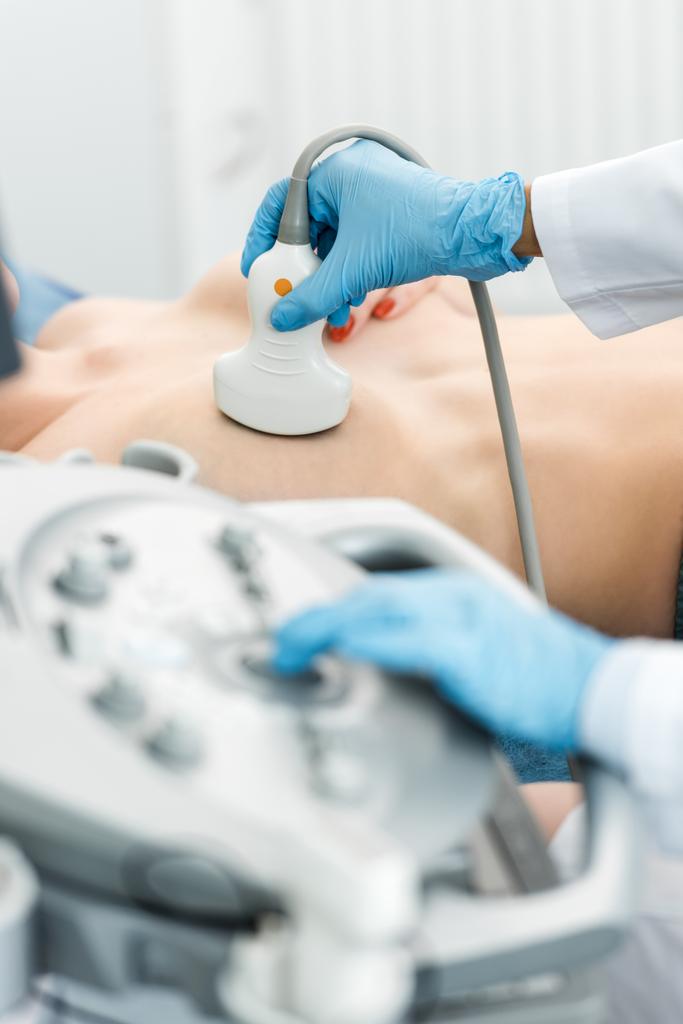 částečný pohled na lékaře, který provádí vyšetření prsu pro pacientku pomocí ultrazvukového skeneru na klinice - Fotografie, Obrázek