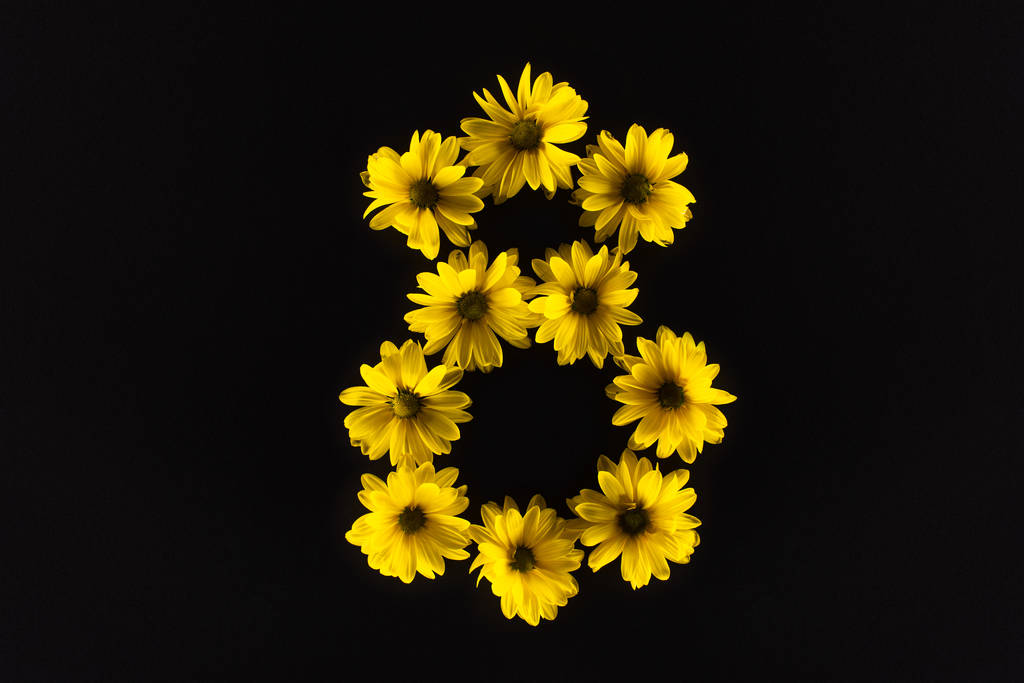 bovenaanzicht van gele madeliefjes gerangschikt in nummer 8 geïsoleerd op zwart - Foto, afbeelding
