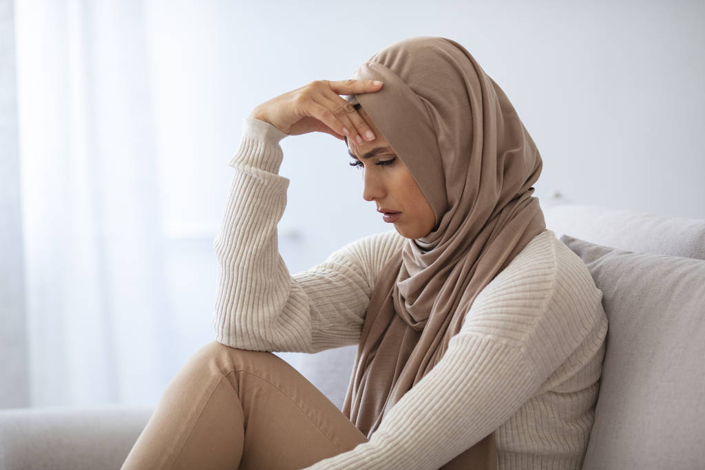 Muslim woman having a headache. Head ache face expression of Muslim woman wearing hijab. Young female feeling headache, suffering migraine symptom, health care, stress - Photo, Image