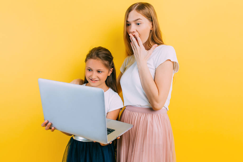 Atractiva madre joven con una hija pequeña, con un ordenador portátil
 - Foto, imagen