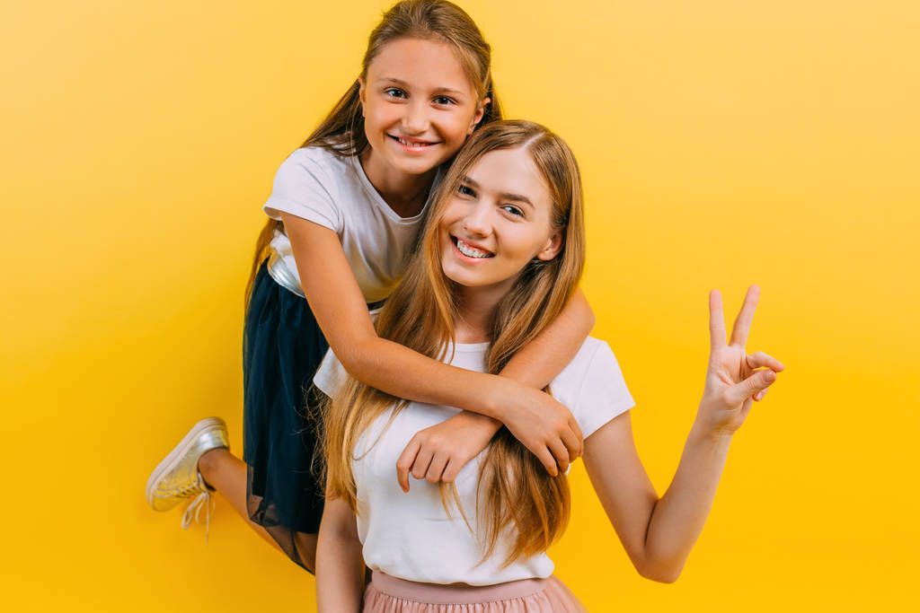 Full-length photo of a beautiful young woman with her little charming daughter, on an isolated yellow background - Photo, Image