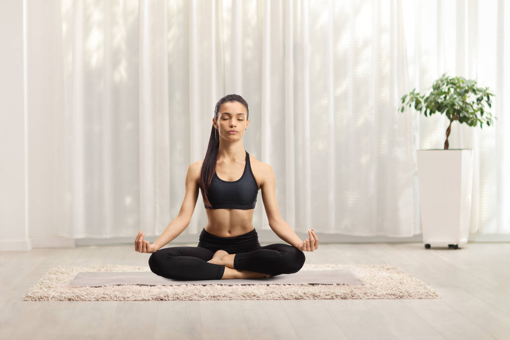 Junge Frau praktiziert Yoga zu Hause  - Foto, Bild