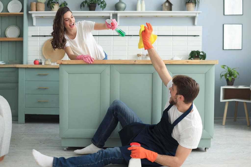 Junges glückliches Paar hat Spaß beim Putzen zu Hause. - Foto, Bild