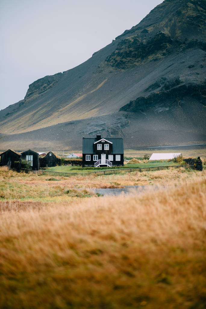 Icelandic autumn landscape with a house against high mountains. - Photo, Image