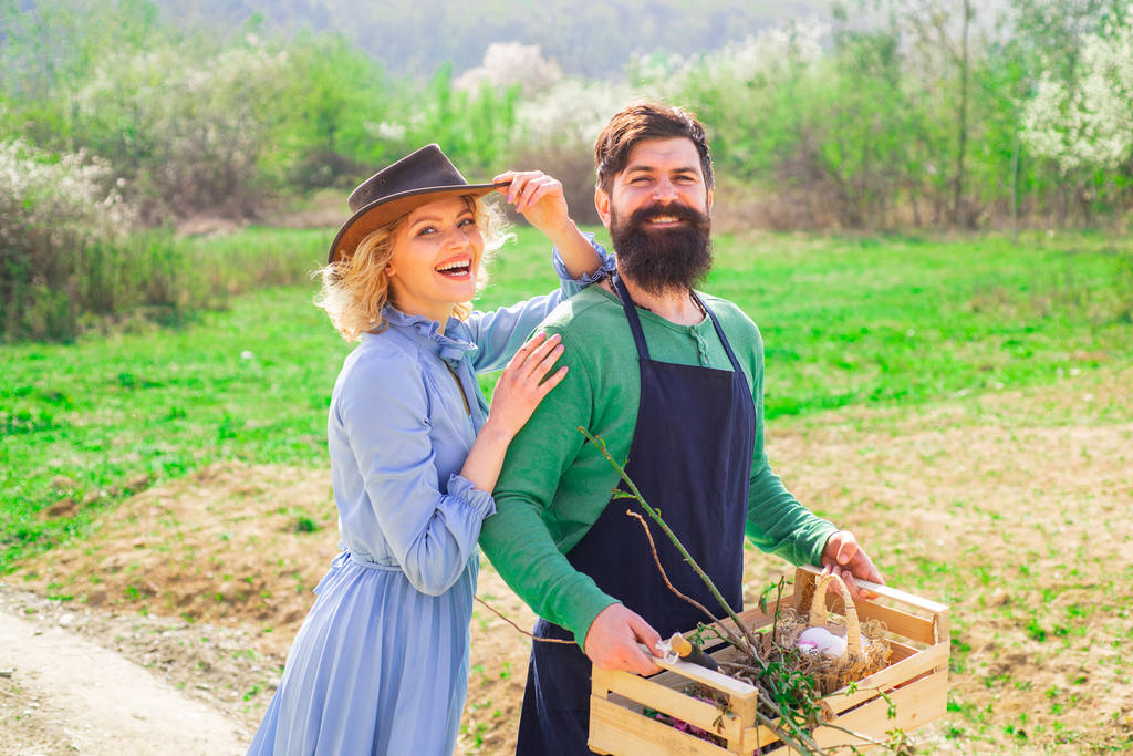 野菜の庭に立っている農民の陽気なカップル。農地で笑顔のカップル。農場で時間を過ごすのが好きだ。畑での作物植え. - 写真・画像