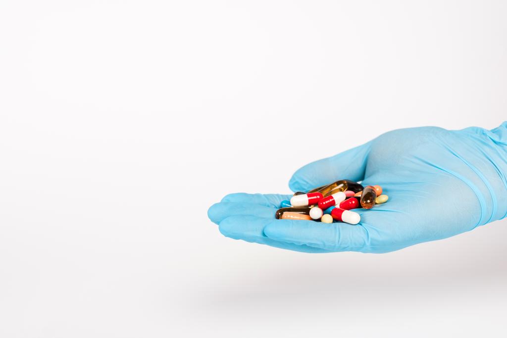 cientista em luva de látex azul segurando pílulas em branco
  - Foto, Imagem