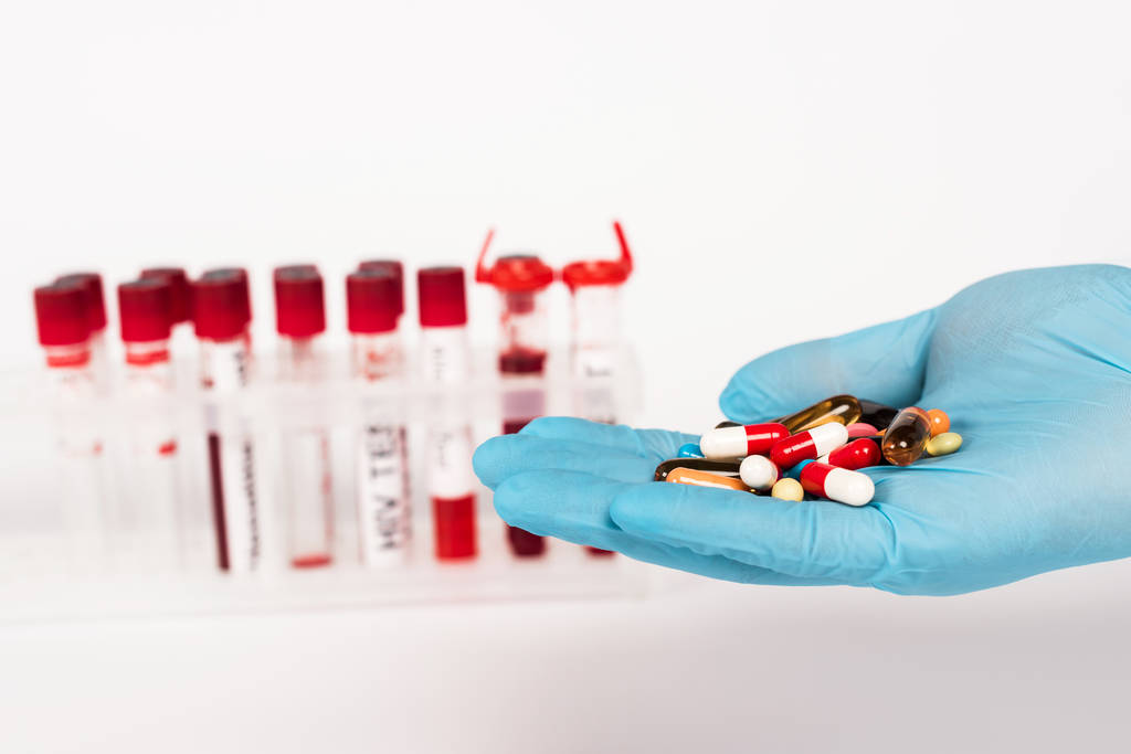 vue recadrée du scientifique en gant de latex tenant des pilules près des éprouvettes avec lettrage sur blanc
  - Photo, image