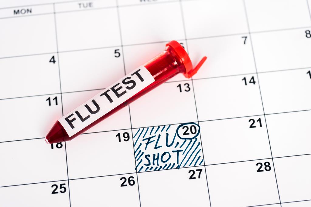δείγμα με δοκιμή γρίπης στο ημερολόγιο με σημειωμένη ημερομηνία και εμβόλιο γρίπης γράμματα  - Φωτογραφία, εικόνα