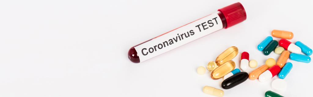 inyección panorámica de píldoras de colores cerca de la muestra con letras de prueba de coronavirus aislados en blanco
  - Foto, imagen