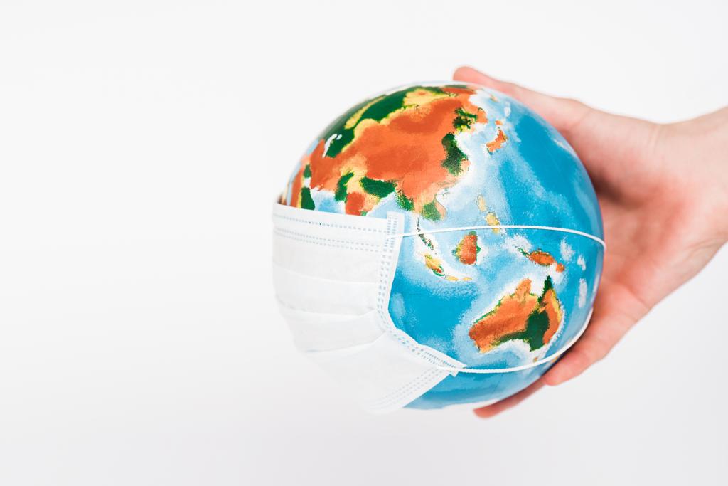 abgeschnittene Ansicht des Menschen mit Globus in Schutzmaske isoliert auf Weiß  - Foto, Bild