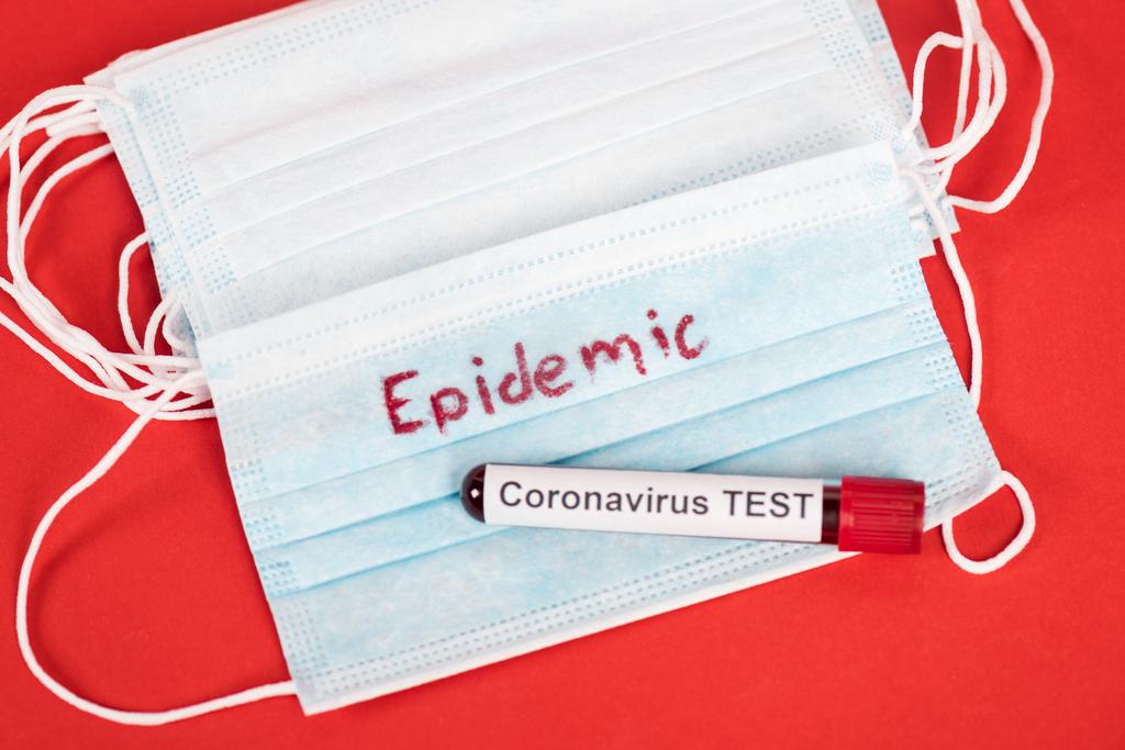 vrchní pohled na vzorek s koronavirovým testem v blízkosti ochranných lékařských masek s epidemickým nápisem na červené  - Fotografie, Obrázek
