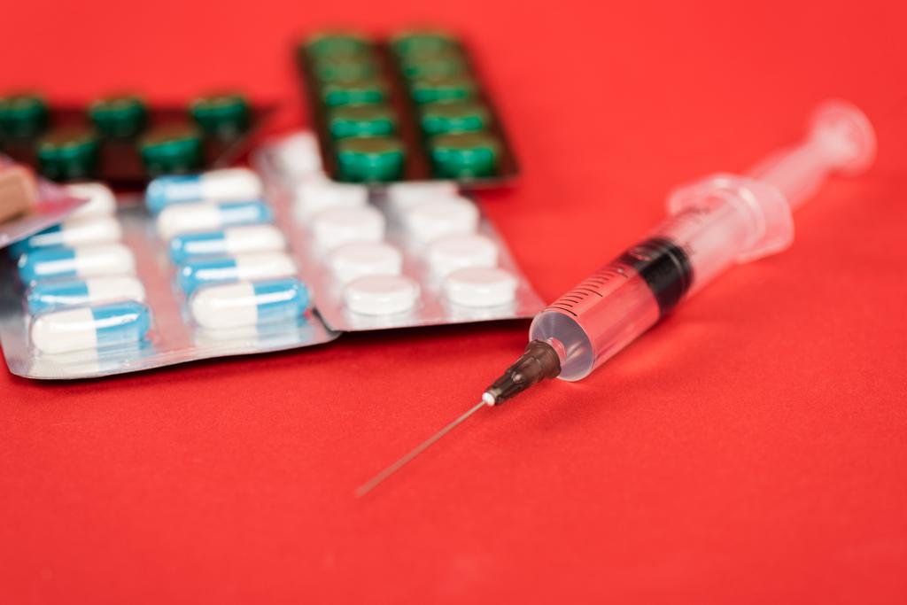 foyer sélectif de la seringue près des pilules sur rouge
  - Photo, image