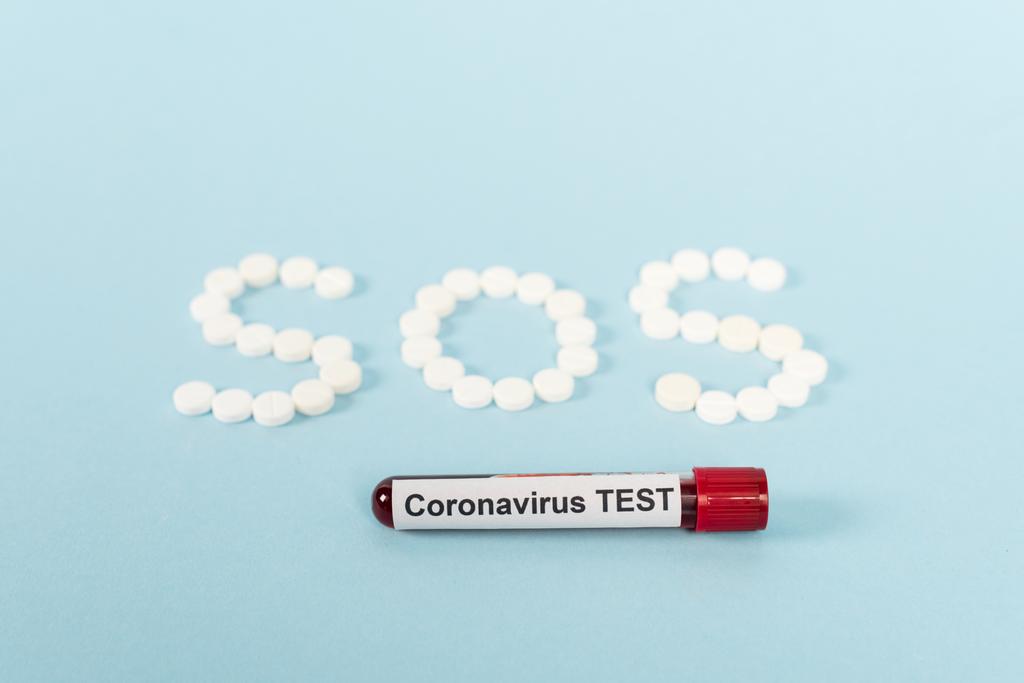 vzorek s koronavirem test v blízkosti pilulek s sos písmem na modré  - Fotografie, Obrázek