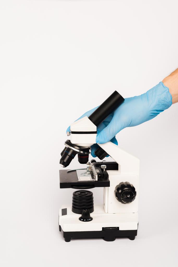 przycięty widok naukowca dotykającego mikroskopu izolowanego na białym  - Zdjęcie, obraz