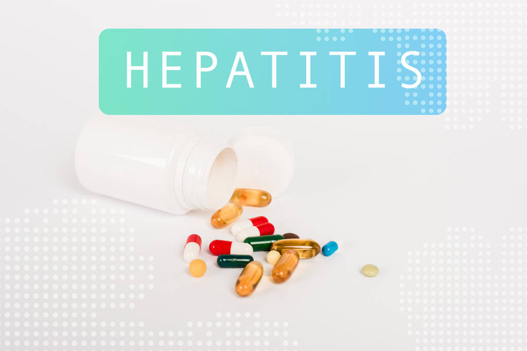 Flasche neben bunten Pillen und Hepatitis-Schriftzug auf weißem Grund - Foto, Bild