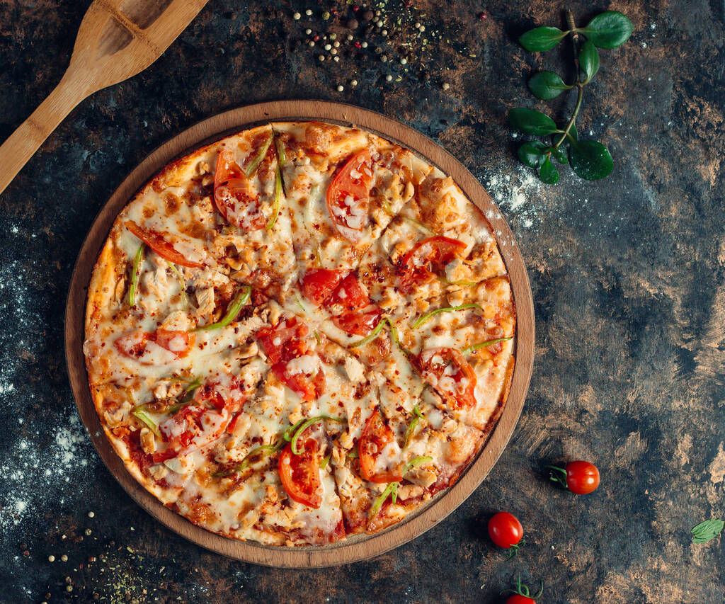 Pizza de frango com pimentão, tomate, queijo em tábua de madeira redonda
 - Foto, Imagem