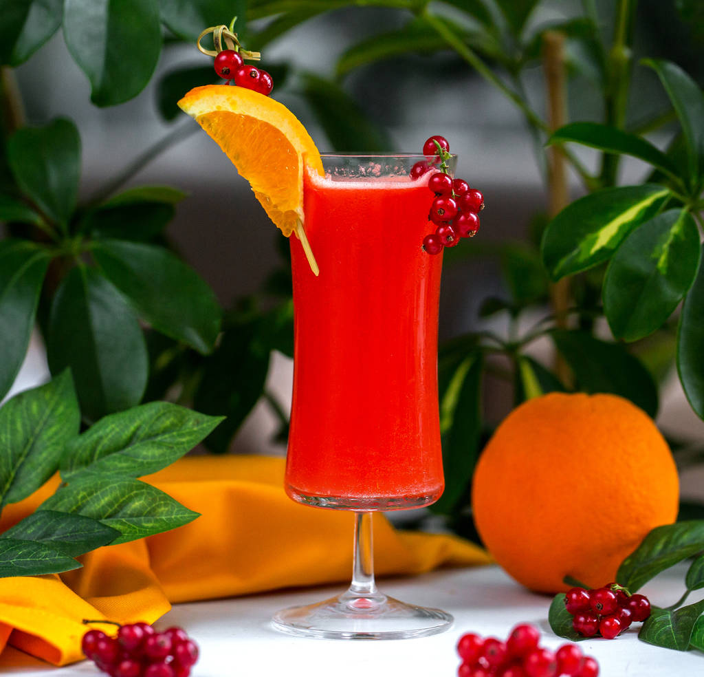 rode cocktail gegarneerd met cranberry en sinaasappelschijfje - Foto, afbeelding