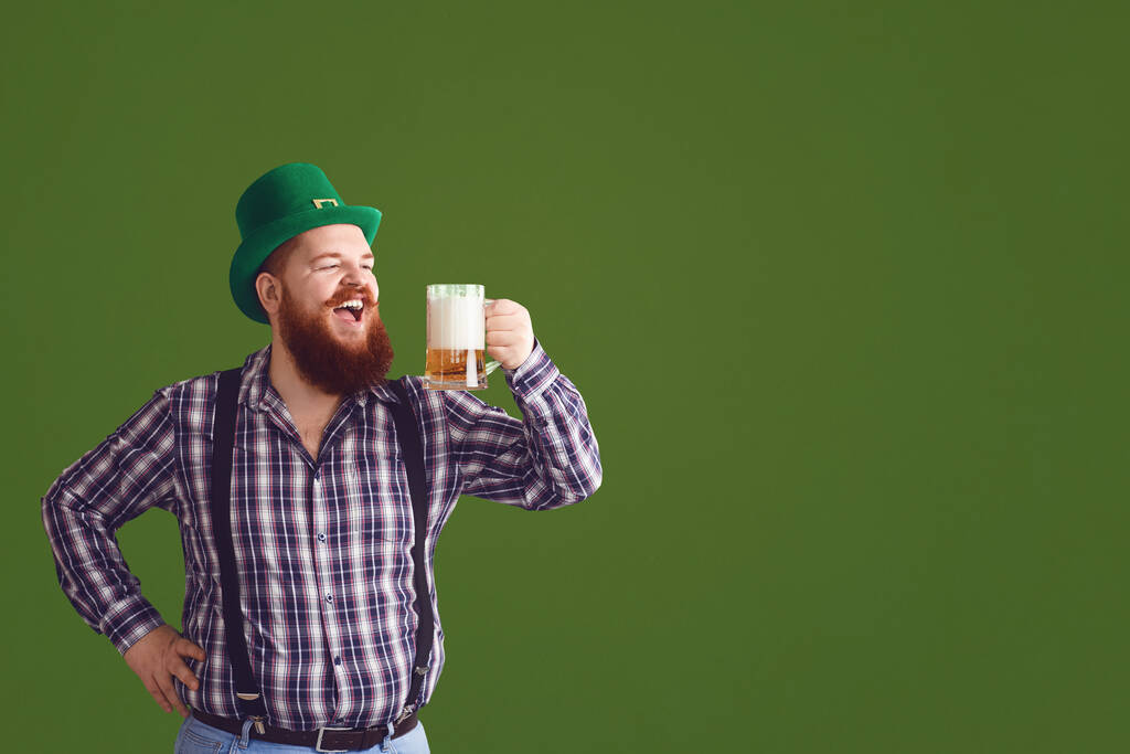 Happy St. Patricks Day. Fat man in a green hat holds his hands up glasses with beer - Photo, Image