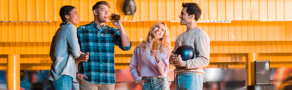 панорамный снимок счастливого многокультурного друга, говорящего и звенящего бутылки пива в луковом клубе
 - Фото, изображение