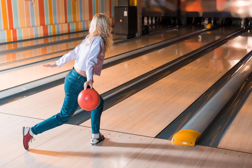 jong blond vrouw gooien bowling bal op kegelbaan - Foto, afbeelding