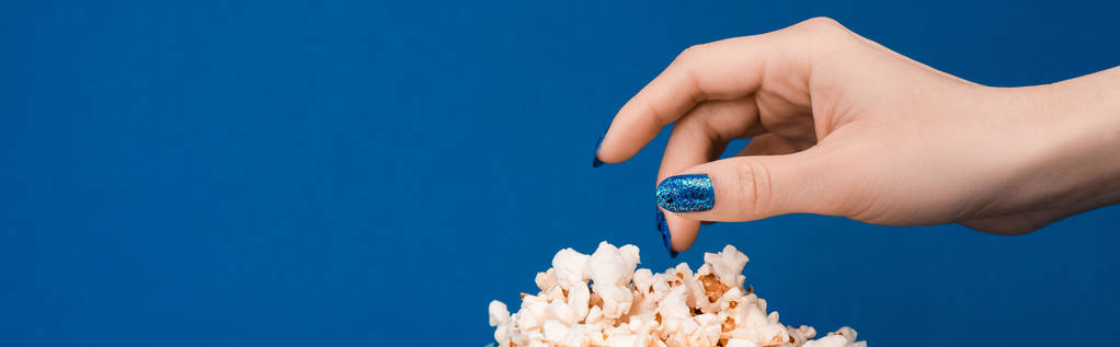panoráma felvétel nő figyelembe popcorn elszigetelt kék  - Fotó, kép
