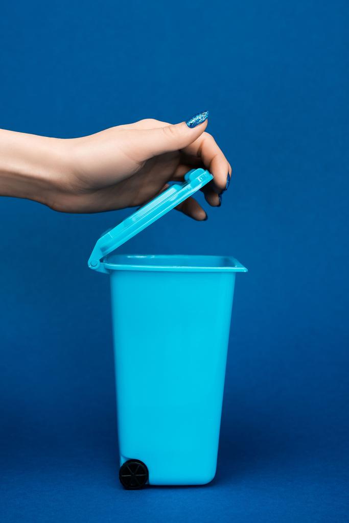 περικοπή άποψη της γυναίκας άνοιγμα σκουπιδοτενεκέ παιχνίδι σε μπλε φόντο  - Φωτογραφία, εικόνα
