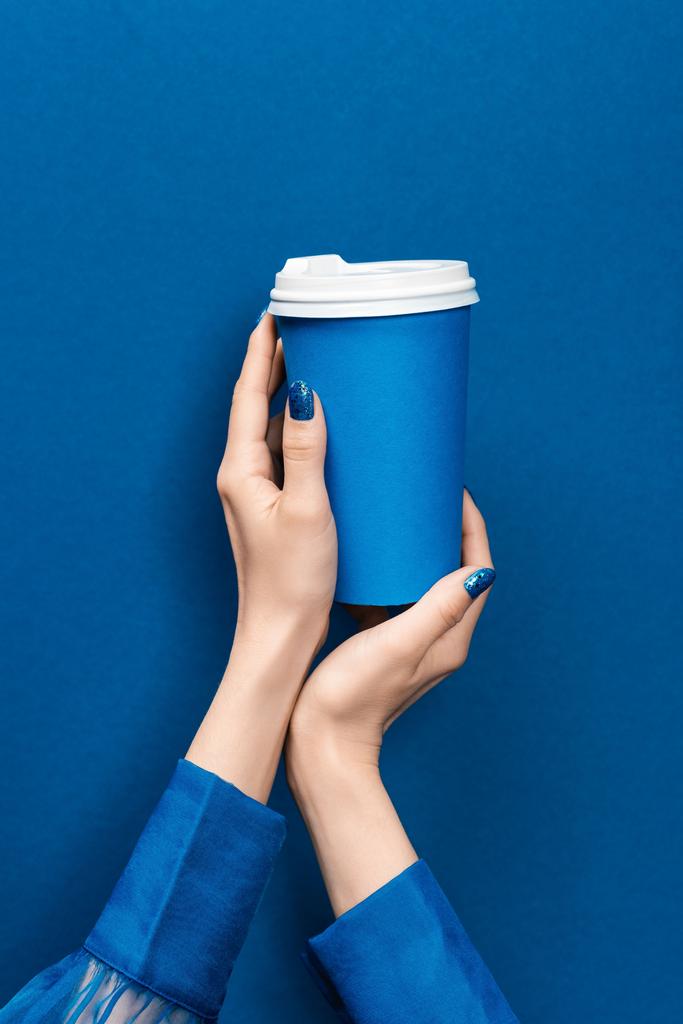 обрізаний вид жінки, що тримає паперову чашку на синьому фоні
  - Фото, зображення