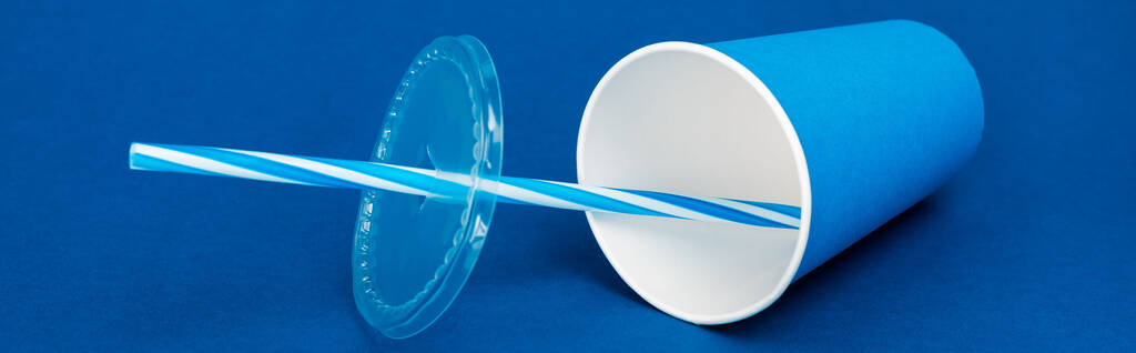 tiro panorâmico de copo de papel com refrigerante no fundo azul
  - Foto, Imagem