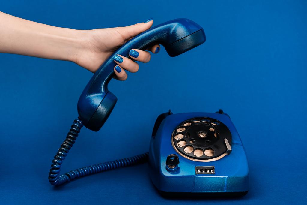 обрезанный вид женщины, держащей телефон на синем фоне
  - Фото, изображение