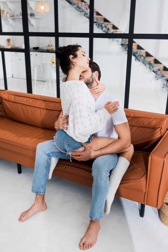 Homem beijando no pescoço sensual namorada no sofá na sala de estar
 - Foto, Imagem