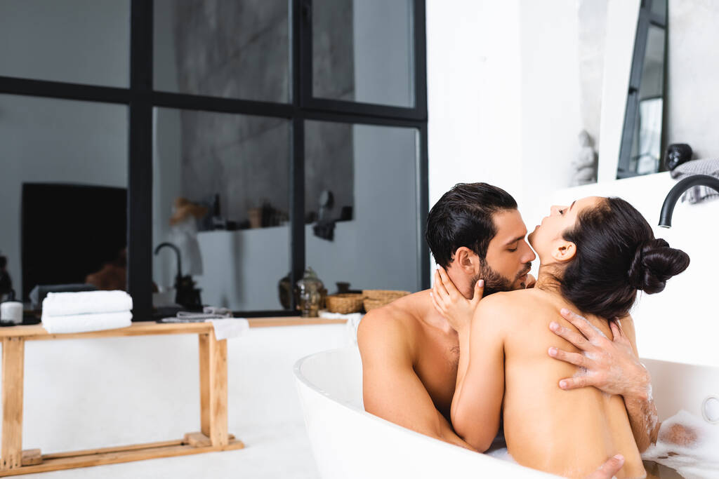 Knappe man zoenen en knuffelen naakte vriendin in bad  - Foto, afbeelding