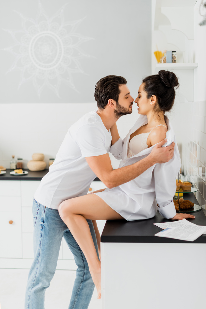 профиль красивого мужчины снимающего рубашку с сексуальной подружки на кухонном столе
 - Фото, изображение