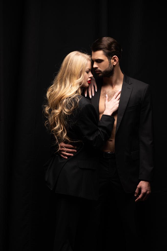 atractiva mujer abrazando guapo hombre aislado en negro
  - Foto, Imagen