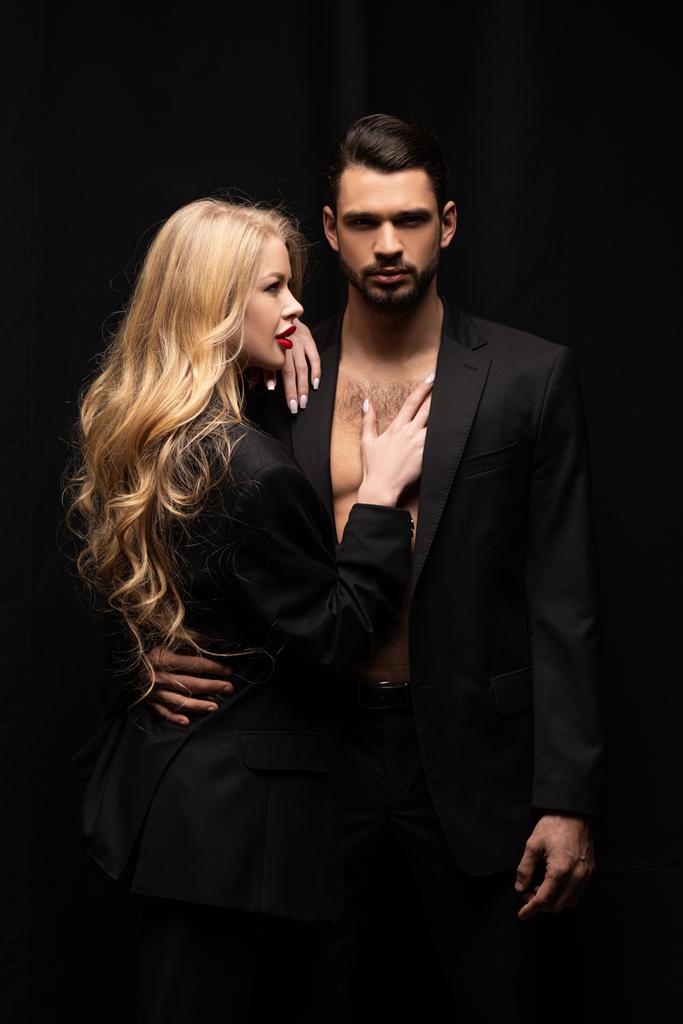 attraente donna riccia toccare bello uomo isolato su nero
  - Foto, immagini