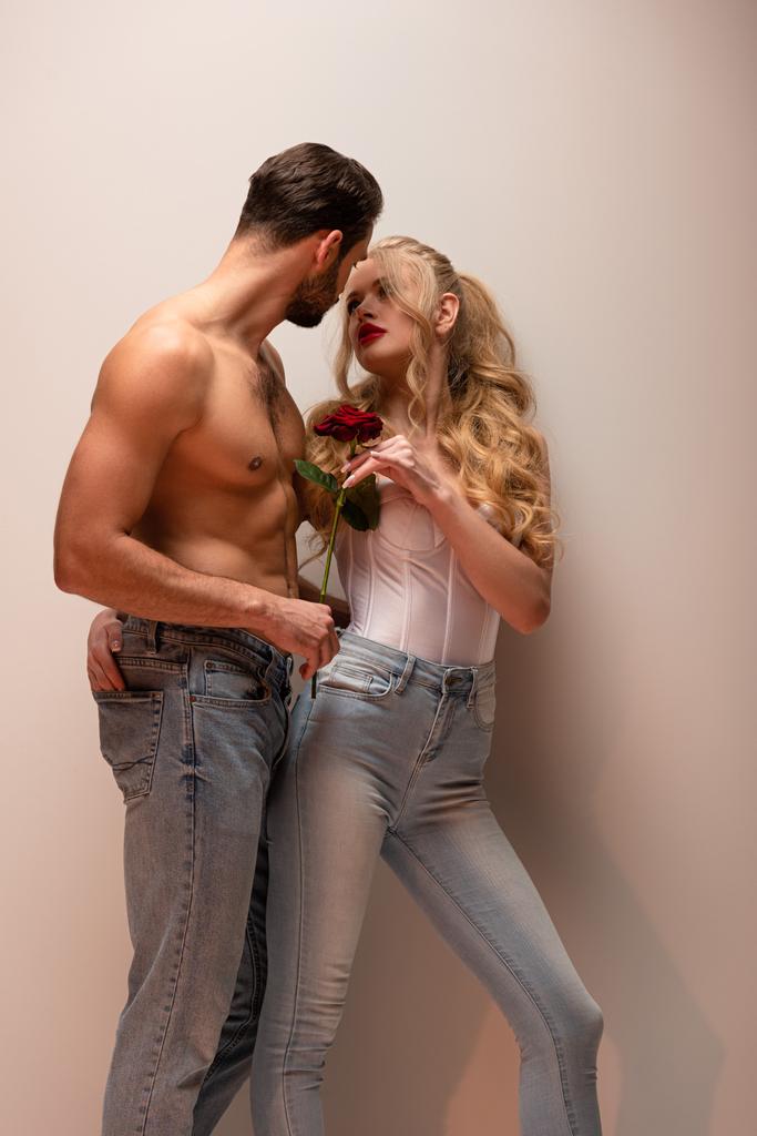 shirtless man holding rose and looking at attractive girl on grey  - Photo, Image