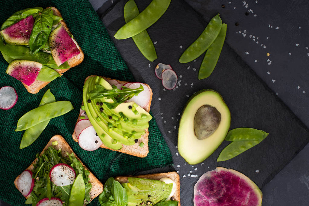Draufsicht auf gesunde Sandwiches mit frischem Gemüse auf Tuch und Steinplatte - Foto, Bild