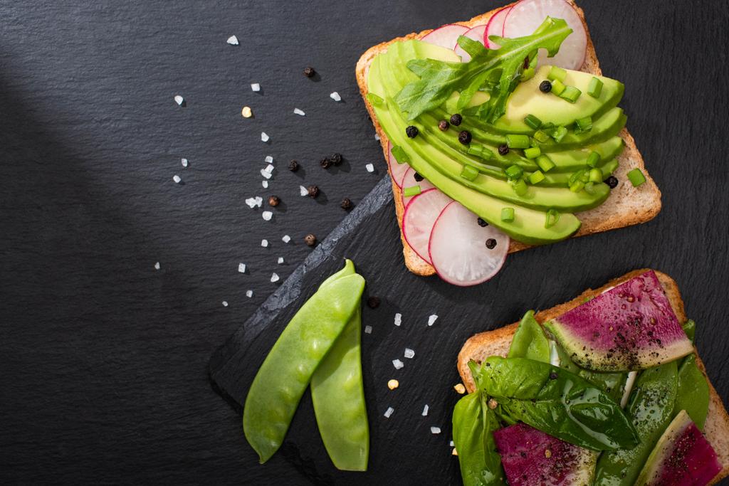 felülnézet friss szendvicsek zöldségek kő fedélzeten borssal és sóval - Fotó, kép